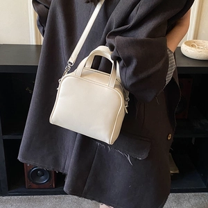 Detail view of cream PU leather Boston handbag with silver hardware and shoulder strap