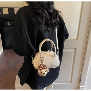 Chic beige leather bowling bag with a cute bear charm shown in a cozy lifestyle setting
