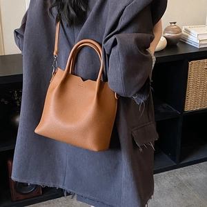 Close-up of brown lychee grain leather tote bag with V-shaped cutout and adjustable strap