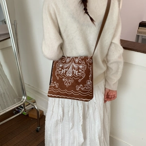 Texture détaillée des broderies sur le sac seau en daim marron pour femmes