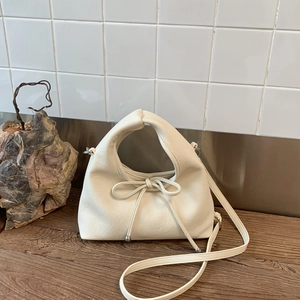 Detail of cream white leather crossbody bag with soft pleats and bow drawstring decor
