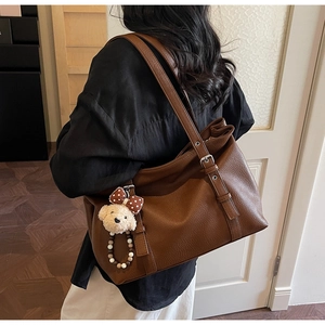Detail of brown lychee grain leather tote bag with a cute plush bear charm accessory