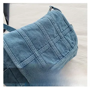 Close-up of vintage blue denim crossbody bag with thick stitching and metal buckle details