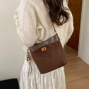 Brown suede bucket bag with zebra tassel charm shown from back view on model