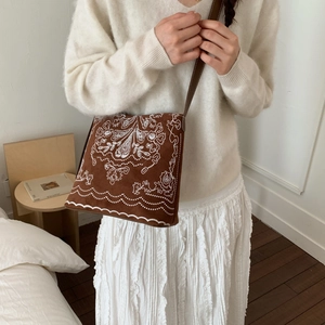 Détail d'un sac bandoulière vintage marron avec broderies florales blanches bohèmes