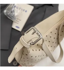 Detailed shot of beige hollow-out shoulder bag featuring silver hardware and luxury texture