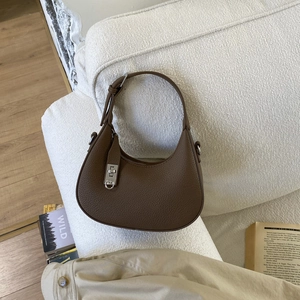 Détail du cuir grainé marron et du fermoir rotatif argenté sur un sac à main en demi-lune