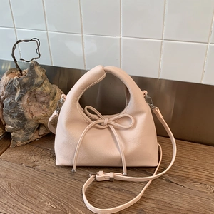 Close-up of pink dumpling bag with pebble leather texture and bow detail