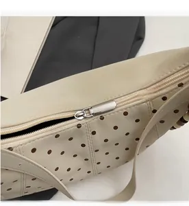 Close-up of smooth silver metal zipper on cream crossbody bag with brown polka dots