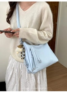 Close-up of light blue crossbody bag with silver ring detail and cute tassel charm