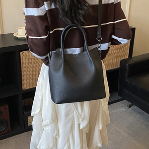 Detail of black lychee grain leather tote bag with adjustable strap for versatile styling