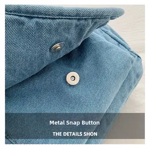 Detailed macro view of the silver magnetic snap closure on a blue denim bag