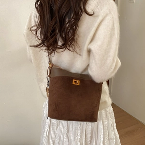 Detail of dark brown suede bucket bag with gold metal twist lock and leather trim texture