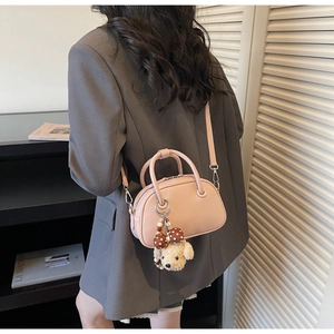 Detail view of pink bowling bag with cute puppy pendant on model in professional blazer