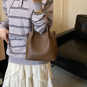 Detail of a brown lychee pattern leather bucket bag with silver metal buckles and handles