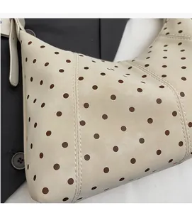 Detailed close-up of beige polka dot shoulder bag with fine vertical stitching and soft texture