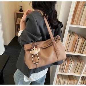 Close-up of caramel leather tote with lychee pattern and cute plush bear charm