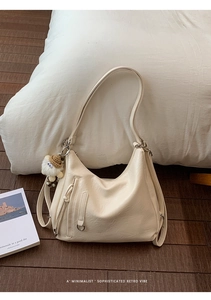 Detail of cream retro shoulder bag with plush lamb charm and versatile strap structure