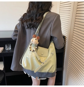 Detail of light green ruched faux leather bag with teddy bear charm on model back