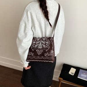 Détail du sac seau en toile marron avec broderie bohème blanche et fine bandoulière