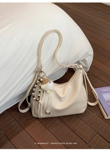 Detail of off-white leather tote bag with stylish pleated design and cute plush charm