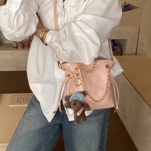 Pink quilted bucket bag with gold chain and cute brown bear charm on female model
