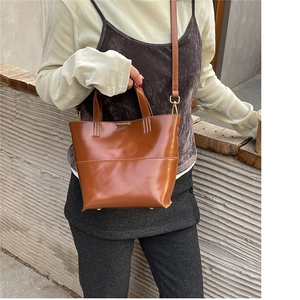 Borsa tote in pelle marrone con hardware in bronzo e tracolla rimovibile su una modella