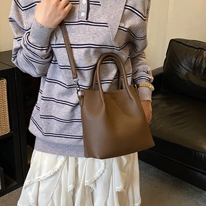 Brown lychee leather bucket bag styled with striped shirt and white skirt