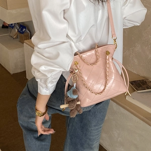 Detail of pink quilted bucket bag with chain handle and cute teddy bear charm