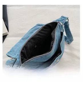 Detail view of denim crossbody bag interior with black fabric lining and metal zipper closure