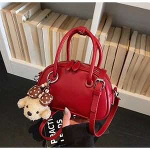 Vintage red bowling boston bag with cute puppy pendant shown against a library background
