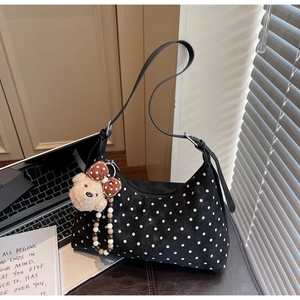 Polka dot hobo bag with cute plush bear pendant and beaded charm on wooden desk