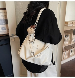 Detail of cream shoulder bag with plush bear charm and beaded pendant on soft faux leather