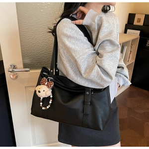 Detail of black lychee grain leather tote bag with cute detachable teddy bear charm