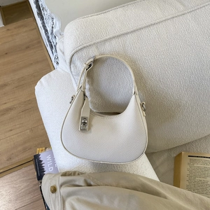 Gros plan sur le cuir grainé crème et le fermoir rotatif en métal argenté du sac selle