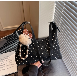 Close-up of black polka dot shoulder bag with cute plush animal charm and beads