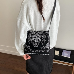Détail du sac seau en toile noire avec broderie ethnique et coutures contrastées