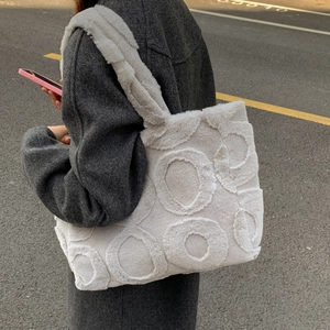 Detail of plush off-white tote bag with raised round patterns and thick shoulder strap