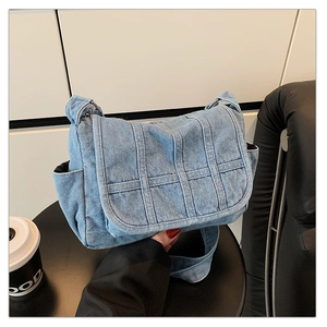 Detail of light blue denim crossbody bag featuring patchwork texture and side pockets