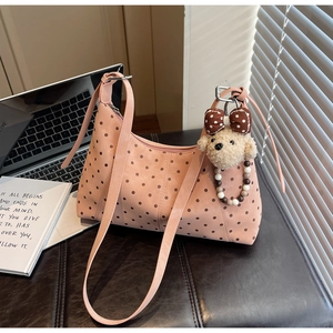 Pink polka dot shoulder bag featuring a cute teddy bear charm and soft laptop background