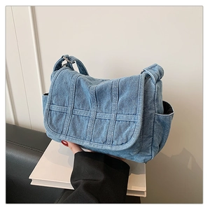 Detail view of denim crossbody bag featuring multi-pocket design and front stripe texture