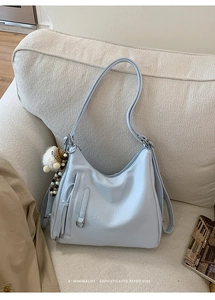 Close-up of light blue hobo bag with leather texture and cute plush lamb charm