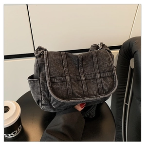 Detailed view of dark gray denim crossbody bag with woven texture and side pocket