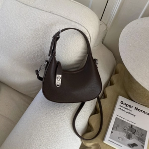 Détails de la texture cuir grainé marron foncé et de la boucle argentée du sac bandoulière