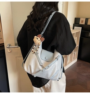 Detail of light blue faux leather shoulder bag with cute plush bear charm and bow