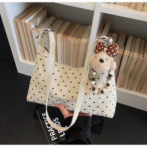 Close-up of creamy white polka dot PU shoulder bag with cute puppy plush charm accessory