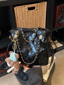 Classic black quilted leather bucket bag with gold chain strap and teddy bear charm