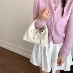 Detail of creamy white leather handbag with elegant bow tie and silver metallic accents