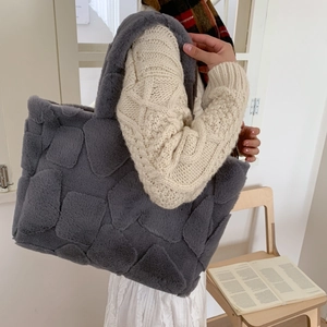 Detail of dark gray plush tote bag featuring geometric embossed pattern and soft texture