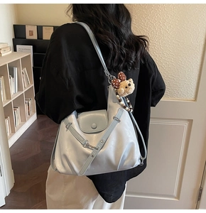Detail of light blue PU leather tote bag with rivet accents and cute bear charm